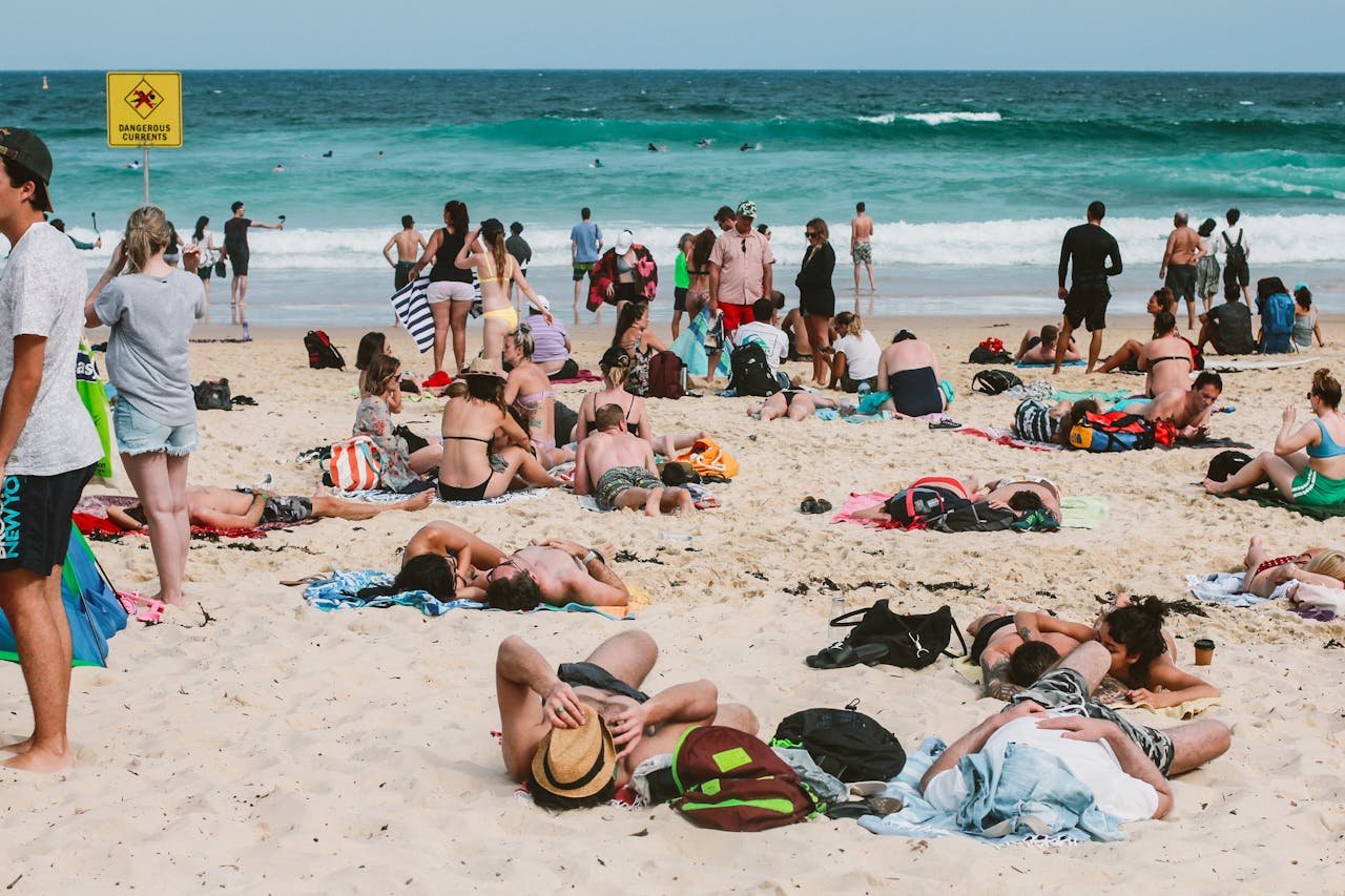 People enjoying a sunny day at Bondi Beach, Australia, with vibrant ocean waves and lively atmosphere.